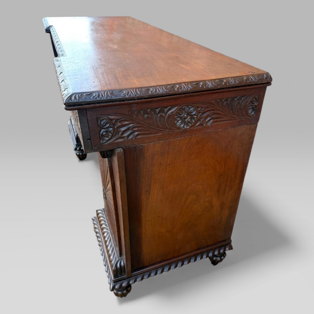 A dark carved padouk wood sideboard featuring intricate floral frieze carvings, sunburst panel pedestals, and a central kneehole design. View IV