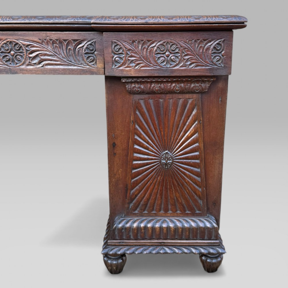 A dark carved padouk wood sideboard featuring intricate floral frieze carvings, sunburst panel pedestals, and a central kneehole design. View VII