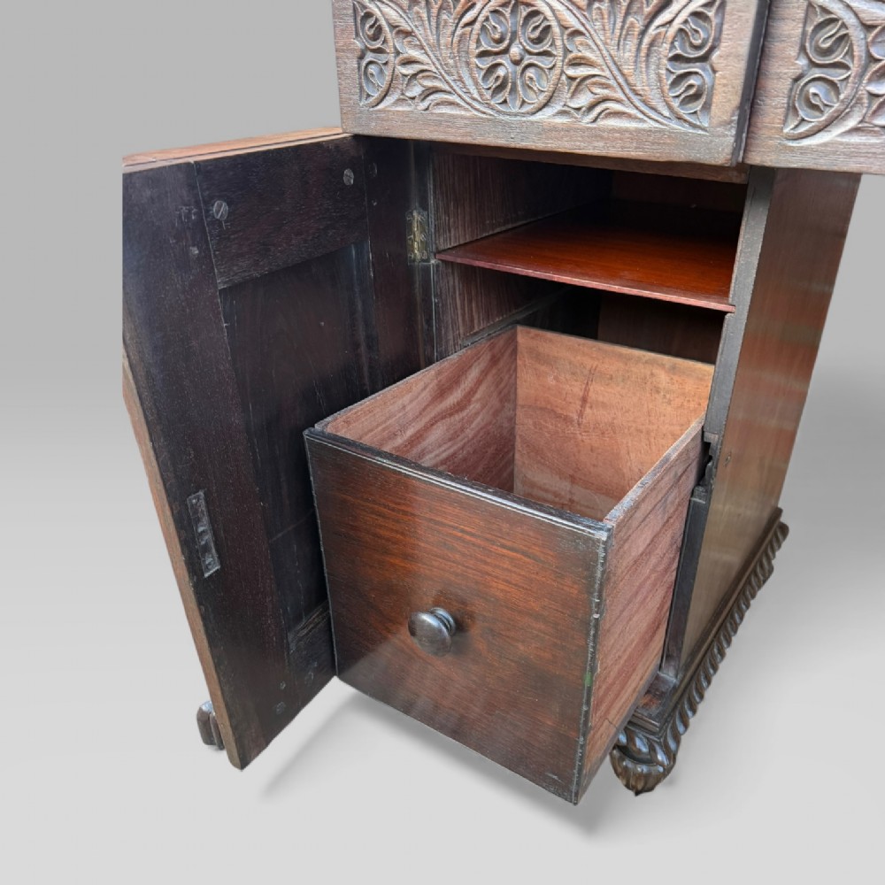 A dark carved padouk wood sideboard featuring intricate floral frieze carvings, sunburst panel pedestals, and a central kneehole design. View IX