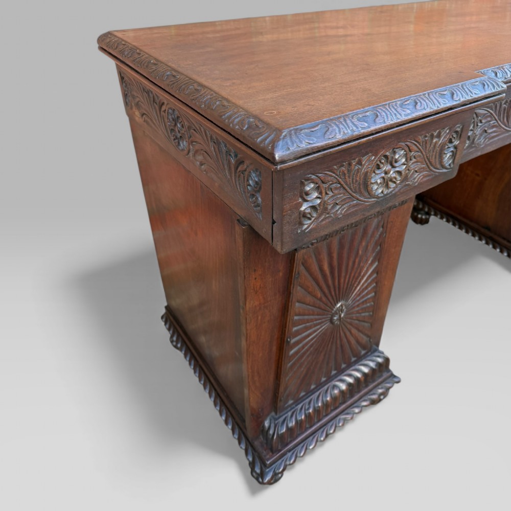 A dark carved padouk wood sideboard featuring intricate floral frieze carvings, sunburst panel pedestals, and a central kneehole design. View XI