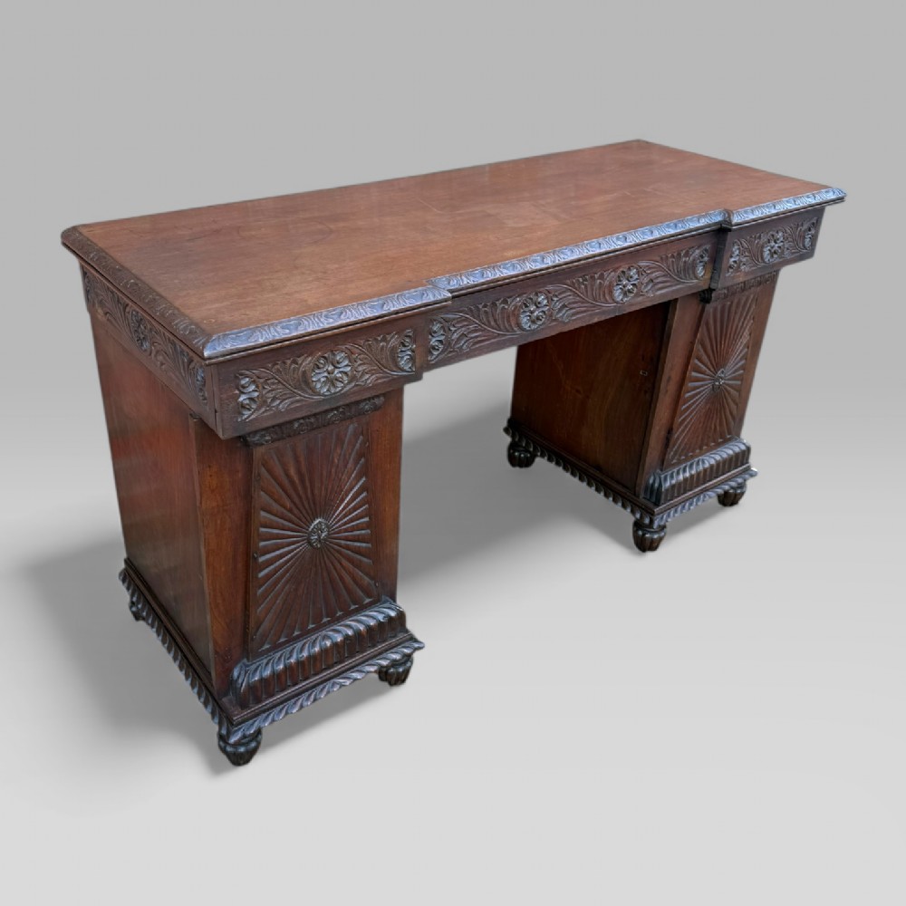 A dark carved padouk wood sideboard featuring intricate floral frieze carvings, sunburst panel pedestals, and a central kneehole design. View XIV