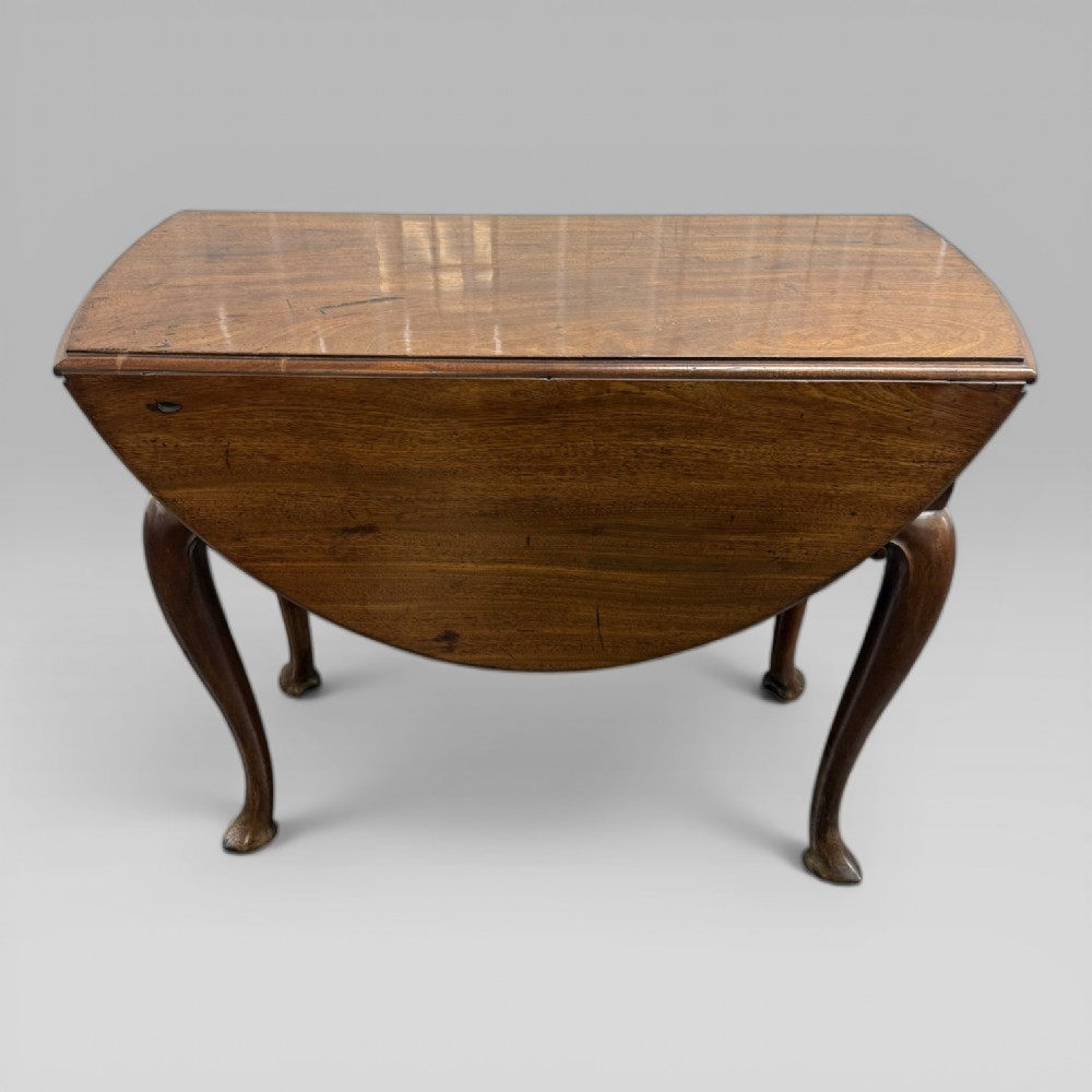 An 18th-century George II mahogany drop-leaf table with hinged oval flaps, cabriole legs terminating in pad feet, and a side drawer with a brass handle. View II