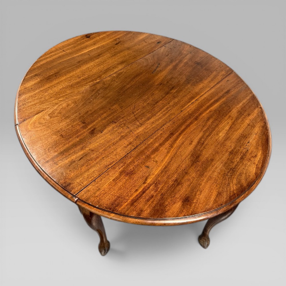 An 18th-century George II mahogany drop-leaf table with hinged oval flaps, cabriole legs terminating in pad feet, and a side drawer with a brass handle. View III