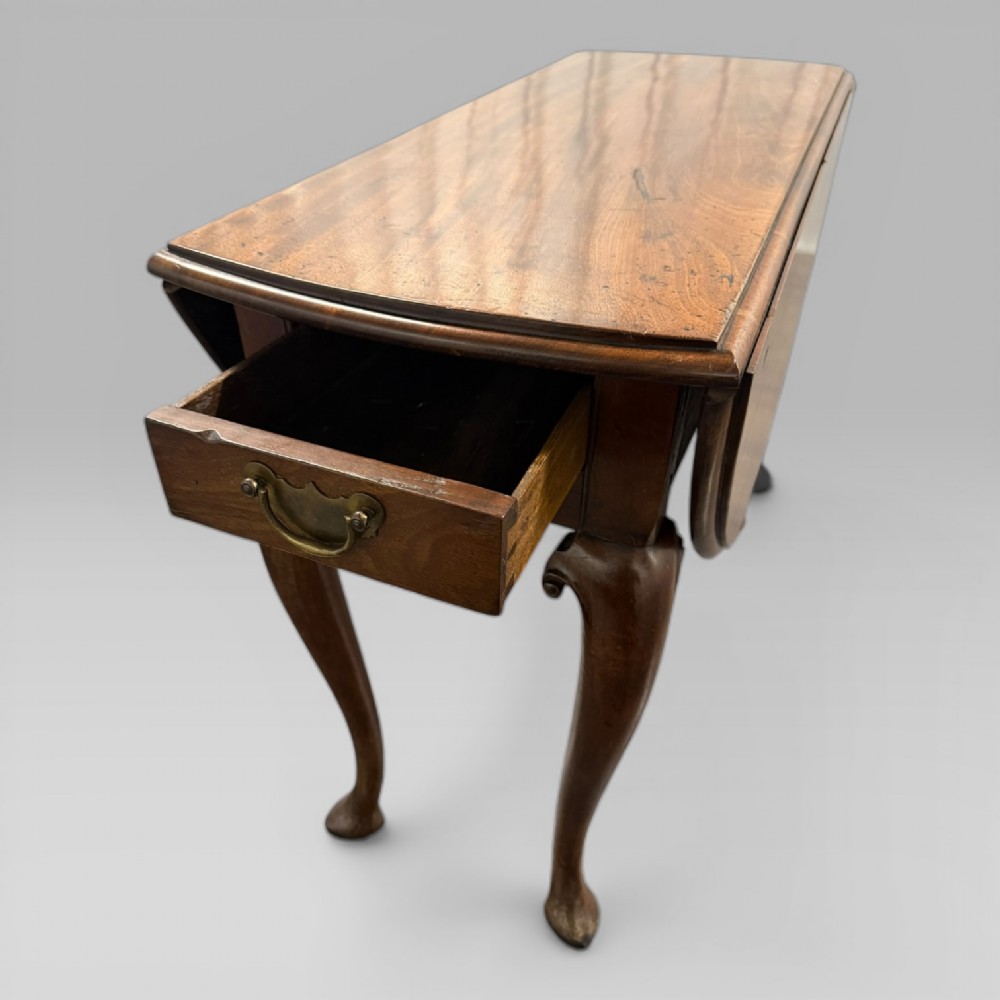 An 18th-century George II mahogany drop-leaf table with hinged oval flaps, cabriole legs terminating in pad feet, and a side drawer with a brass handle. View VI