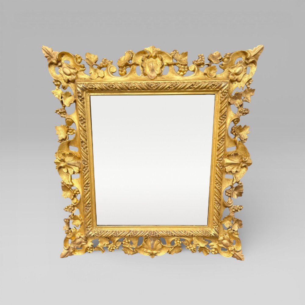 An ornate Victorian rectangular wall mirror featuring an intricately carved giltwood frame with openwork floral and scroll motifs.