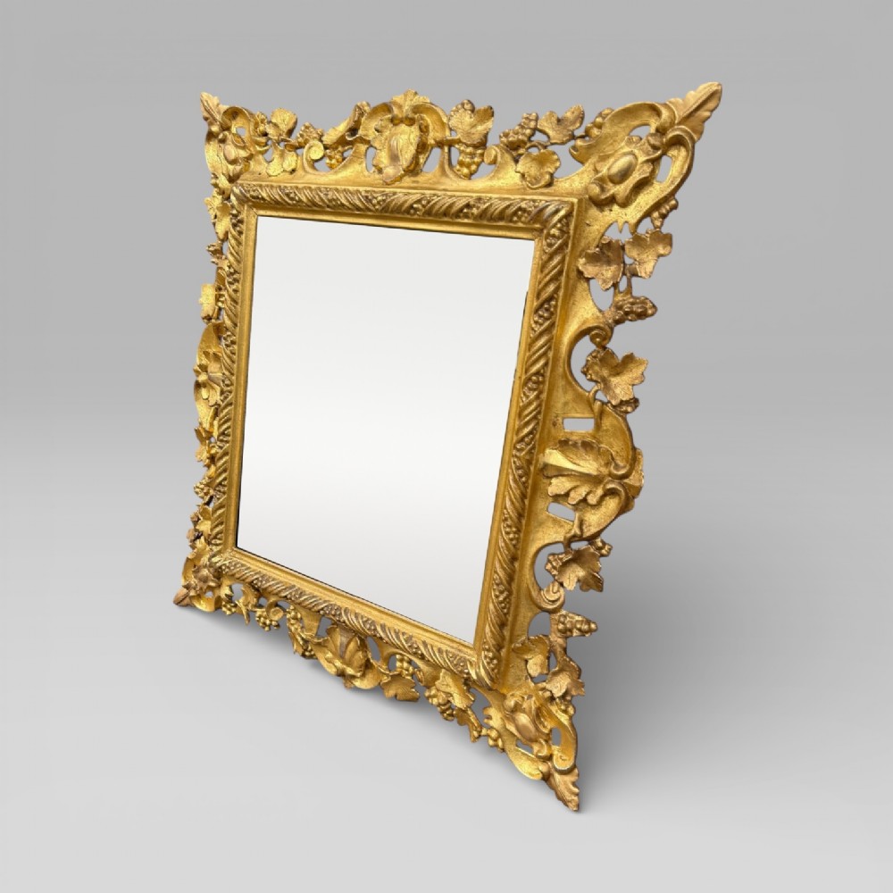 An ornate Victorian rectangular wall mirror featuring an intricately carved giltwood frame with openwork floral and scroll motifs. View II