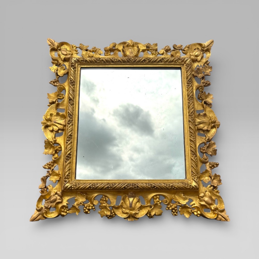 An ornate Victorian rectangular wall mirror featuring an intricately carved giltwood frame with openwork floral and scroll motifs. View IV