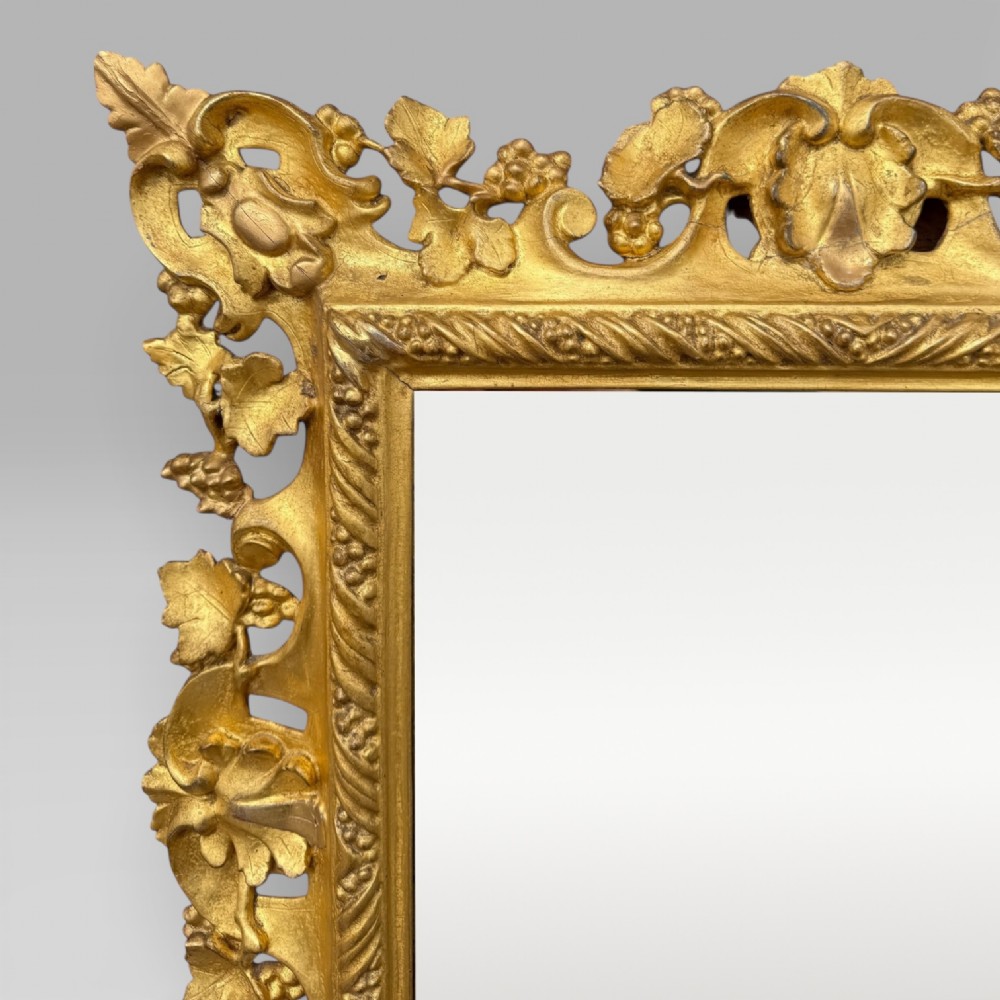 An ornate Victorian rectangular wall mirror featuring an intricately carved giltwood frame with openwork floral and scroll motifs. View V