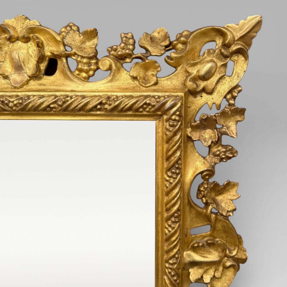 An ornate Victorian rectangular wall mirror featuring an intricately carved giltwood frame with openwork floral and scroll motifs. View VI