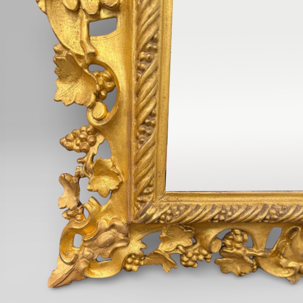 An ornate Victorian rectangular wall mirror featuring an intricately carved giltwood frame with openwork floral and scroll motifs. View VII