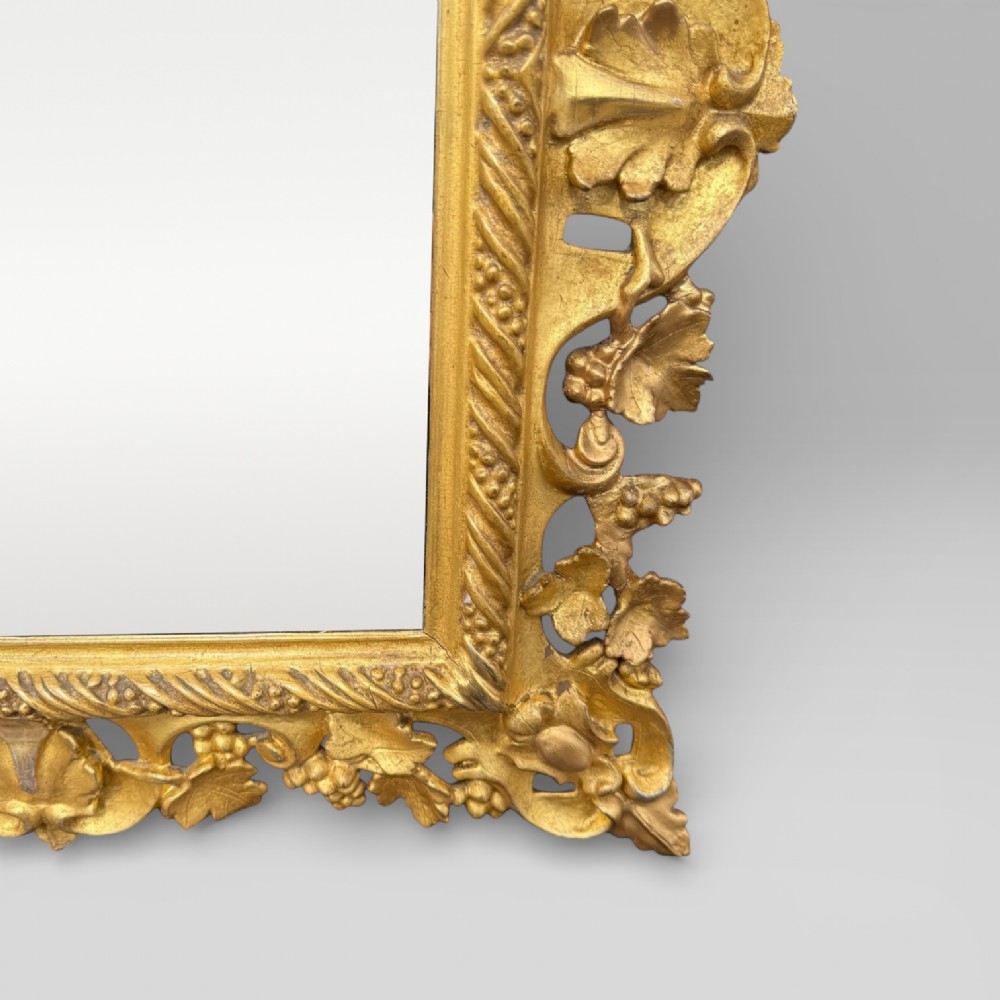 An ornate Victorian rectangular wall mirror featuring an intricately carved giltwood frame with openwork floral and scroll motifs. View VIII