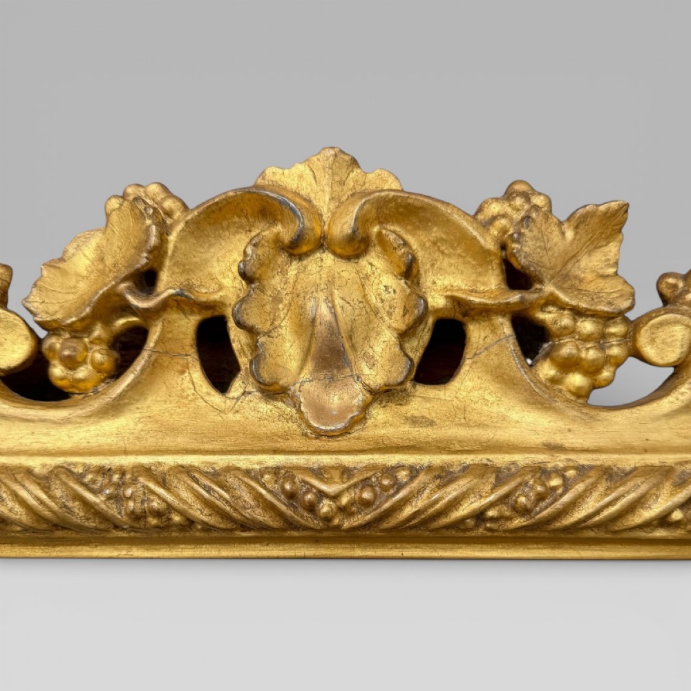 An ornate Victorian rectangular wall mirror featuring an intricately carved giltwood frame with openwork floral and scroll motifs. View IX