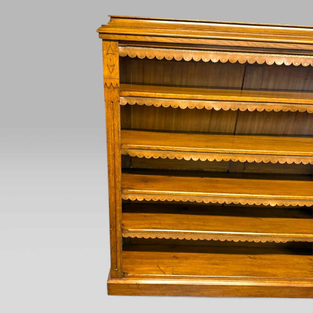 A late Victorian open bookcase crafted from golden oak, featuring scalloped edging along each shelf and subtle geometric carvings on the pilasters. View III