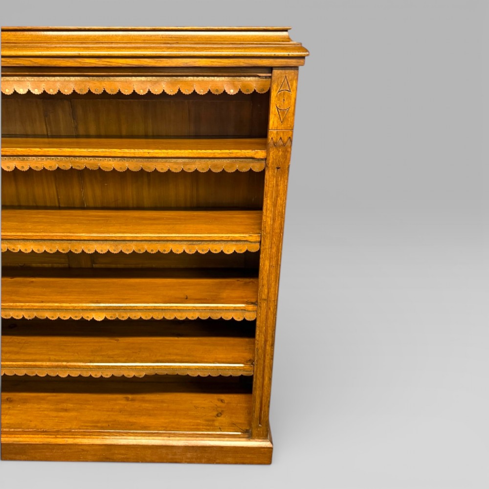 A late Victorian open bookcase crafted from golden oak, featuring scalloped edging along each shelf and subtle geometric carvings on the pilasters. View IV