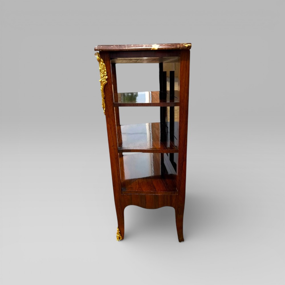 A French Louis XV style rosewood open side cabinet featuring a red marble top, three tiered shelves, and decorative brass ormolu mounts. View XIV