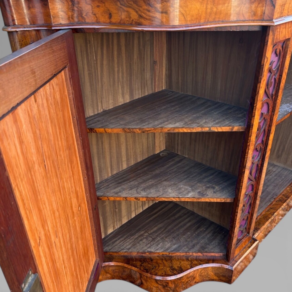 A Victorian walnut credenza featuring a breakfront white marble top, an arched crest-carved mirror frame, and base panels detailed with an oval mirror and fabric behind fretwork. View VIII