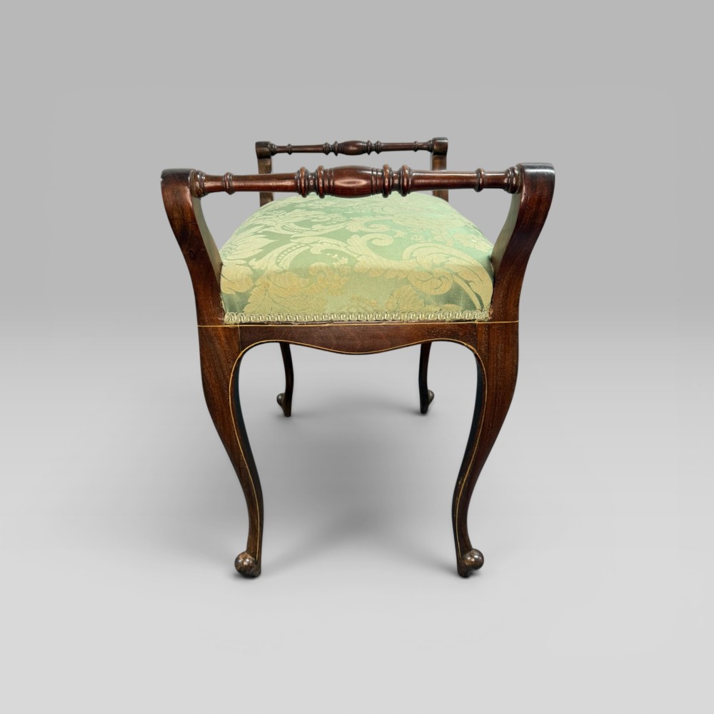 An antique mahogany piano stool featuring cabriole legs, fine line inlay, turned handles, and green floral damask upholstered seating. View VII