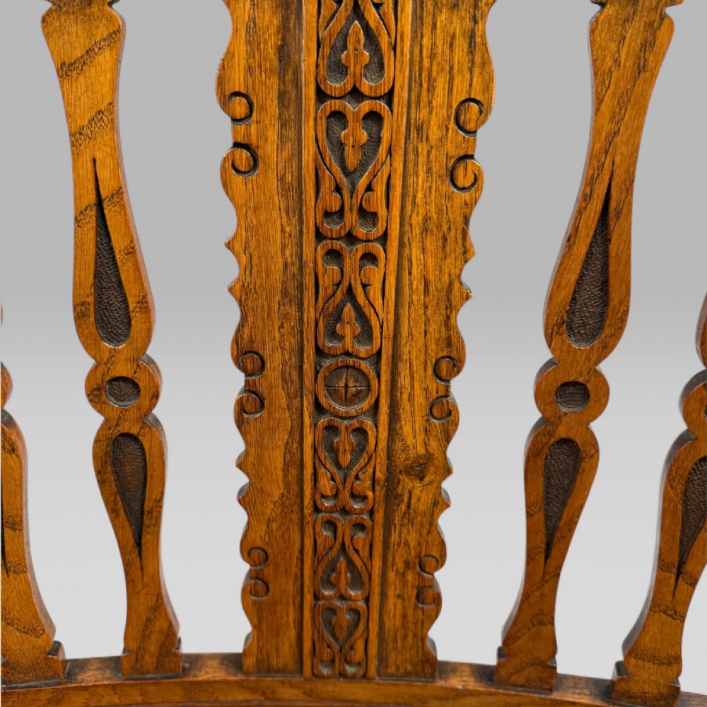 A Victorian carved golden oak armchair featuring a pierced vertical slat backrest, sculpted armrests, turned legs, and a brown leather seat. View VIII