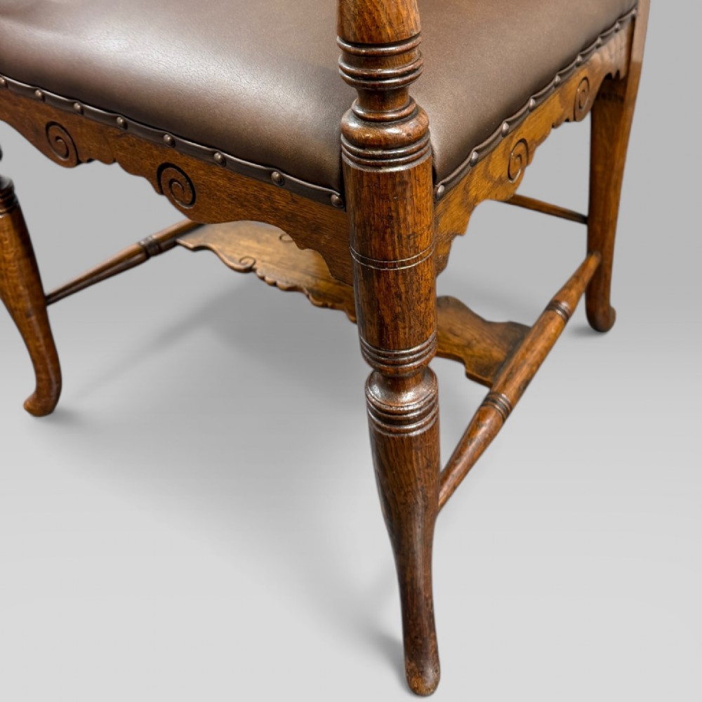 A Victorian carved golden oak armchair featuring a pierced vertical slat backrest, sculpted armrests, turned legs, and a brown leather seat. View X