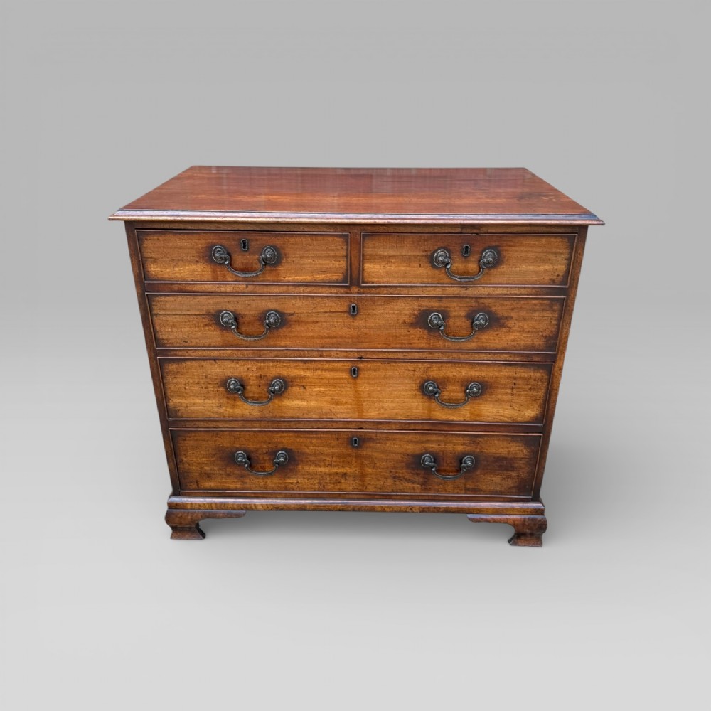 A late 18th-century George III mahogany chest of drawers featuring two short over three long drawers with brass swan-neck handles and bracket feet.