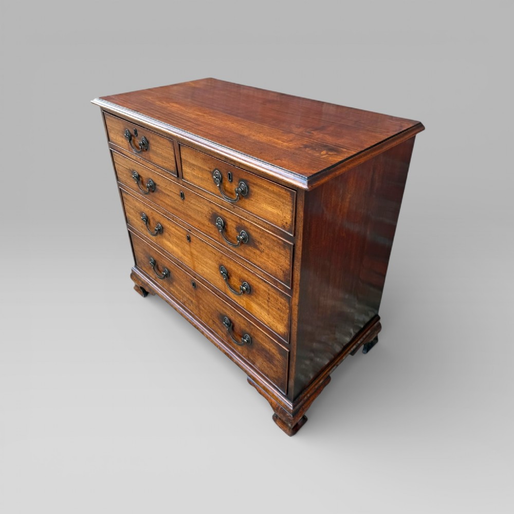 A late 18th-century George III mahogany chest of drawers featuring two short over three long drawers with brass swan-neck handles and bracket feet. View II