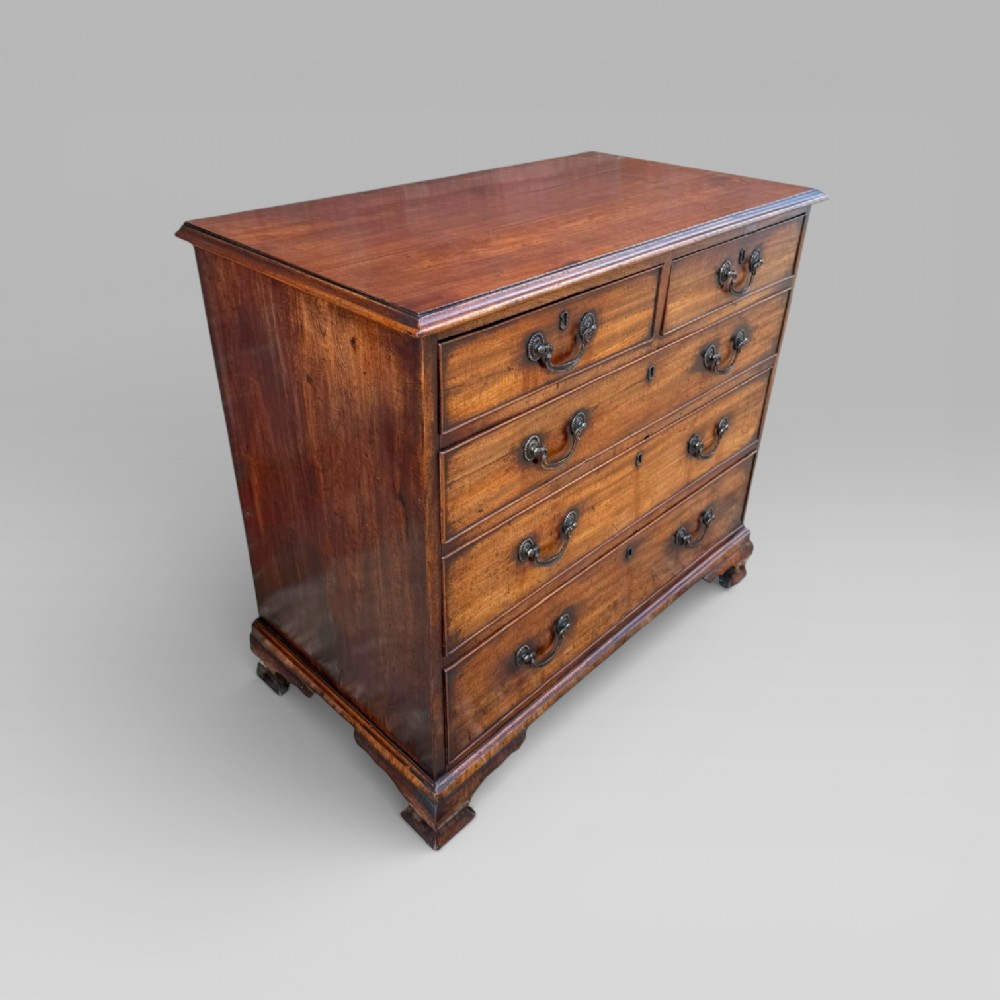 A late 18th-century George III mahogany chest of drawers featuring two short over three long drawers with brass swan-neck handles and bracket feet. View III