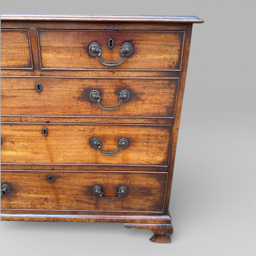 A late 18th-century George III mahogany chest of drawers featuring two short over three long drawers with brass swan-neck handles and bracket feet. View IV
