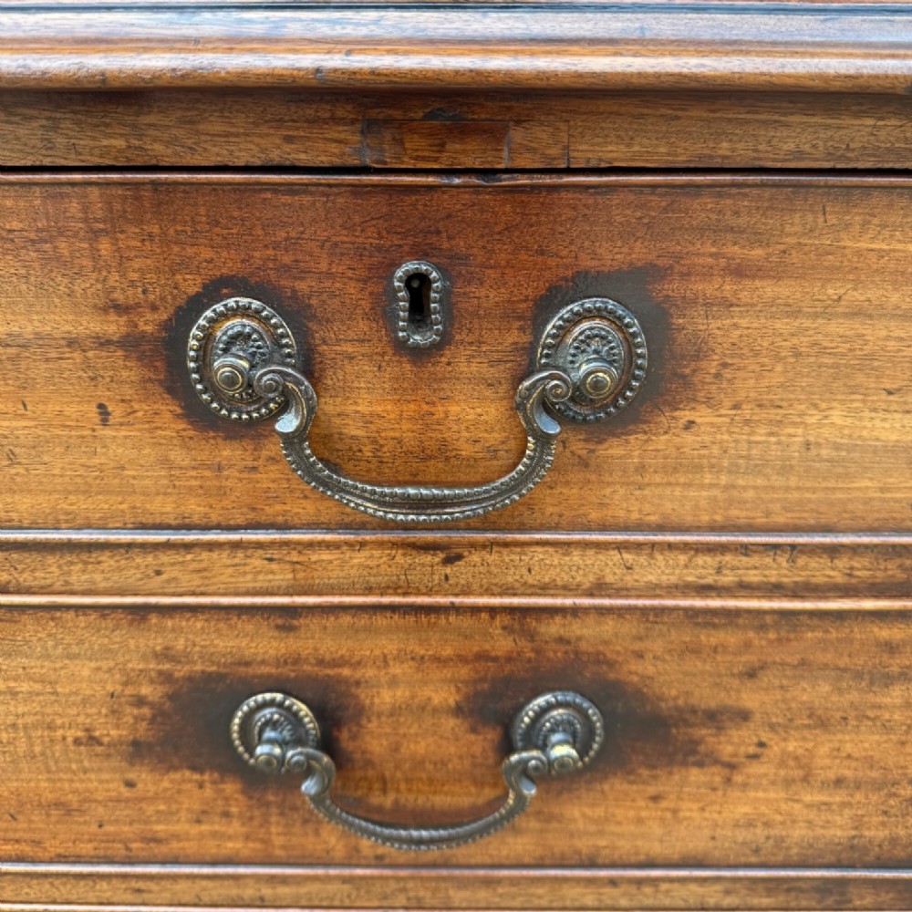 A late 18th-century George III mahogany chest of drawers featuring two short over three long drawers with brass swan-neck handles and bracket feet. View X