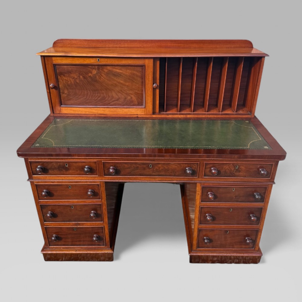 A Victorian mahogany pedestal desk featuring a green tooled leather writing surface, nine drawers with turned handles, and a raised upper cupboard superstructure. View II