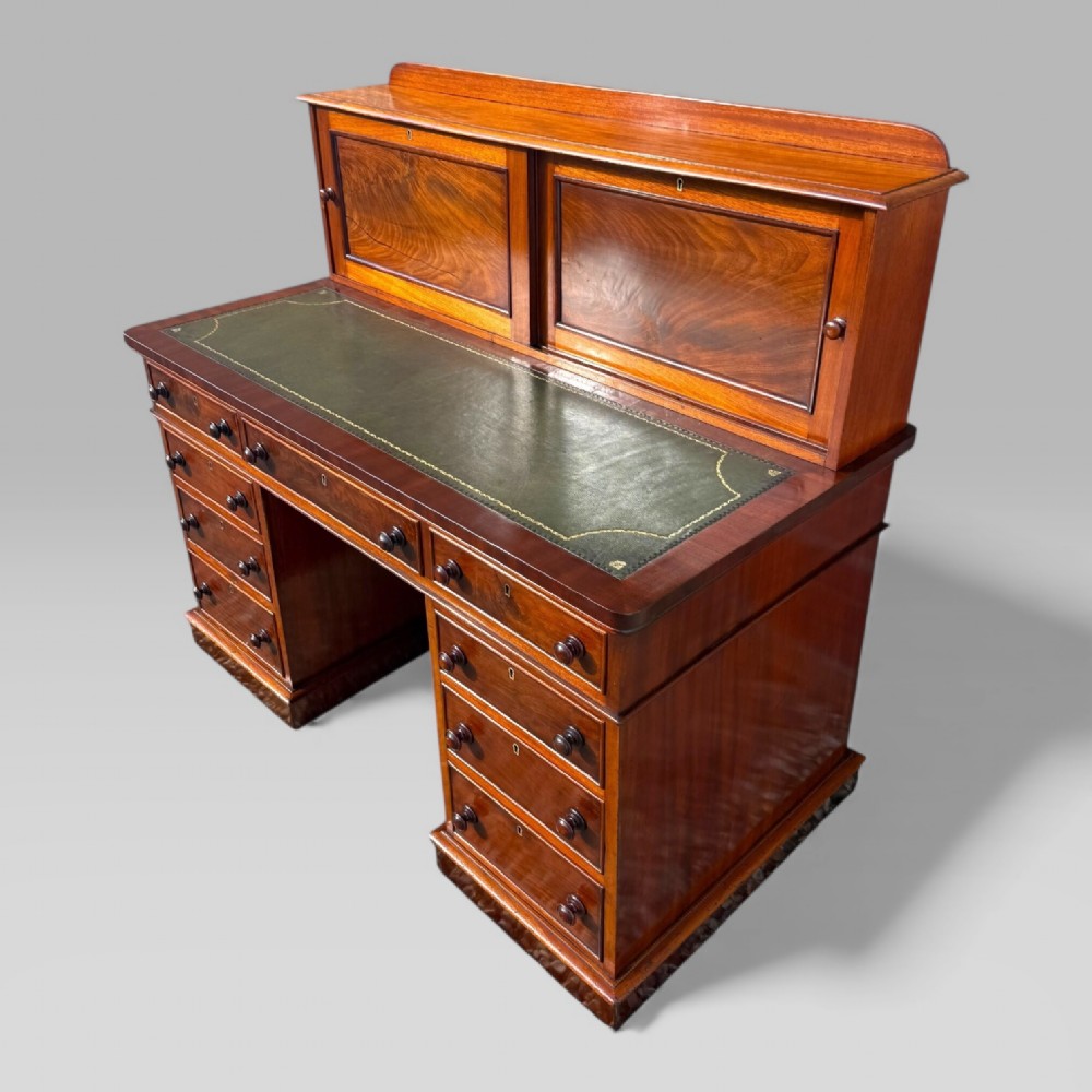 A Victorian mahogany pedestal desk featuring a green tooled leather writing surface, nine drawers with turned handles, and a raised upper cupboard superstructure. View III