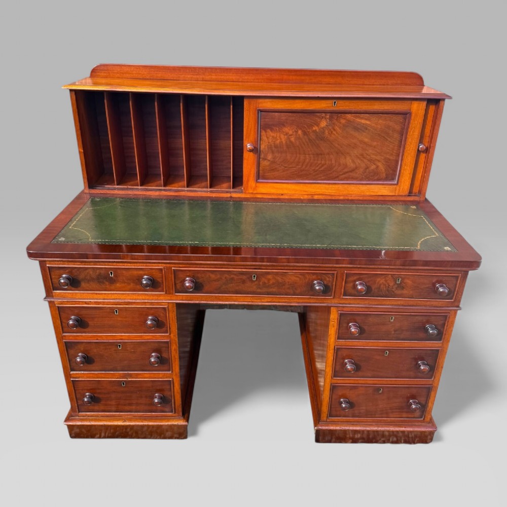 A Victorian mahogany pedestal desk featuring a green tooled leather writing surface, nine drawers with turned handles, and a raised upper cupboard superstructure. View IV