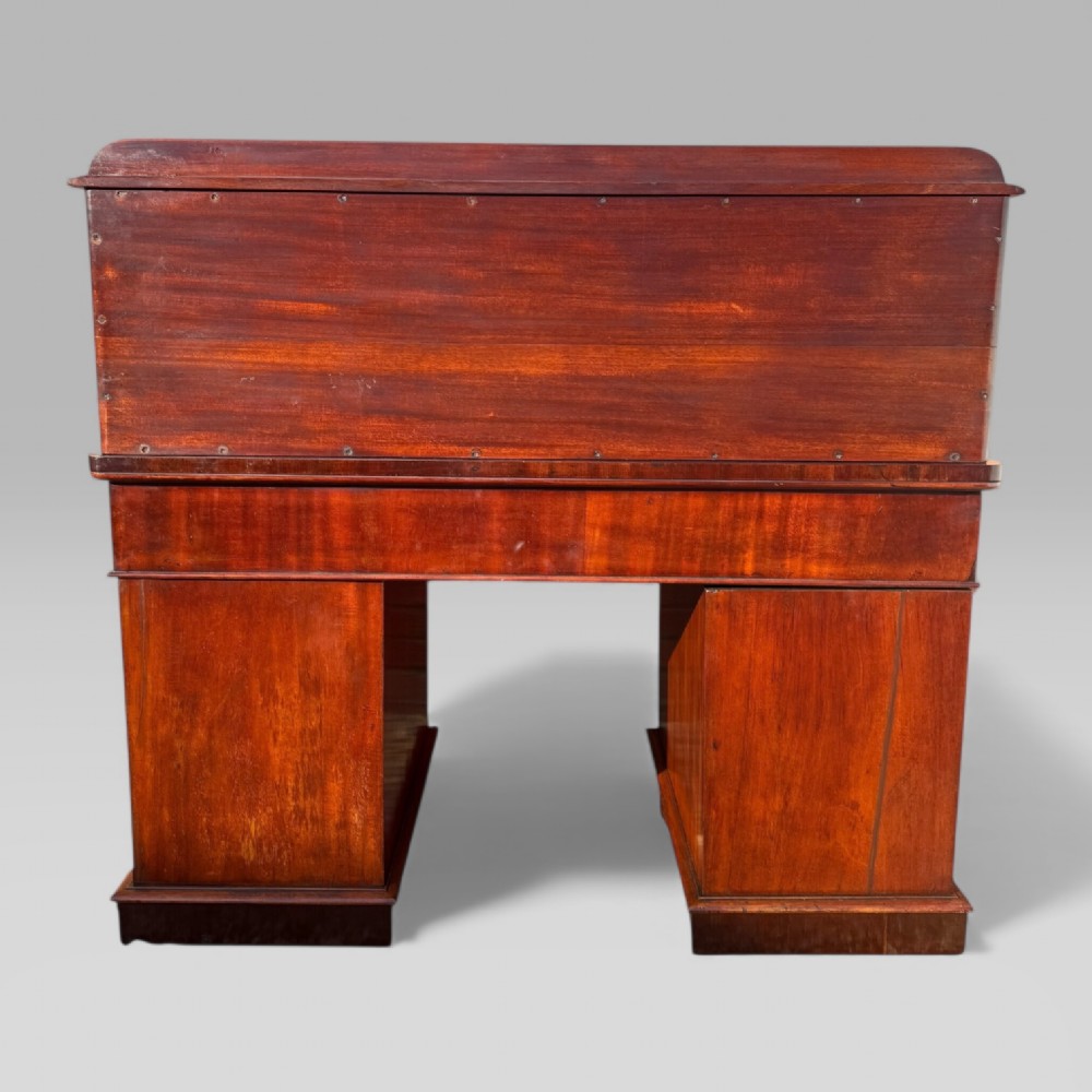 A Victorian mahogany pedestal desk featuring a green tooled leather writing surface, nine drawers with turned handles, and a raised upper cupboard superstructure. View VI
