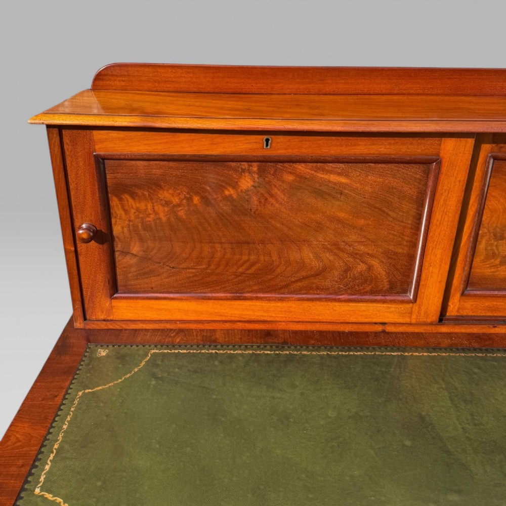 A Victorian mahogany pedestal desk featuring a green tooled leather writing surface, nine drawers with turned handles, and a raised upper cupboard superstructure. View VII