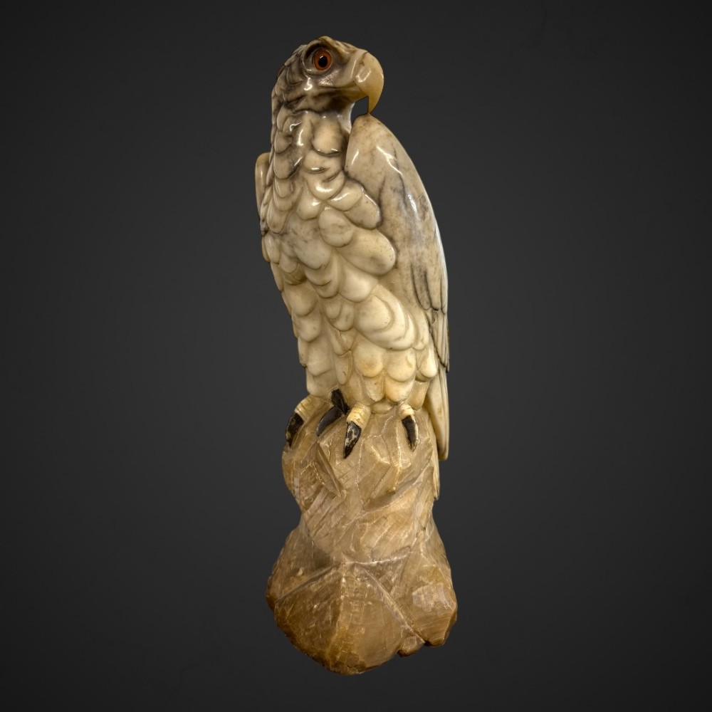 A 19th-century carved veined white marble eagle statue with amber glass eyes perched atop a rock formation. View II