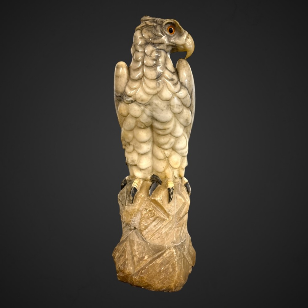 A 19th-century carved veined white marble eagle statue with amber glass eyes perched atop a rock formation. View IV