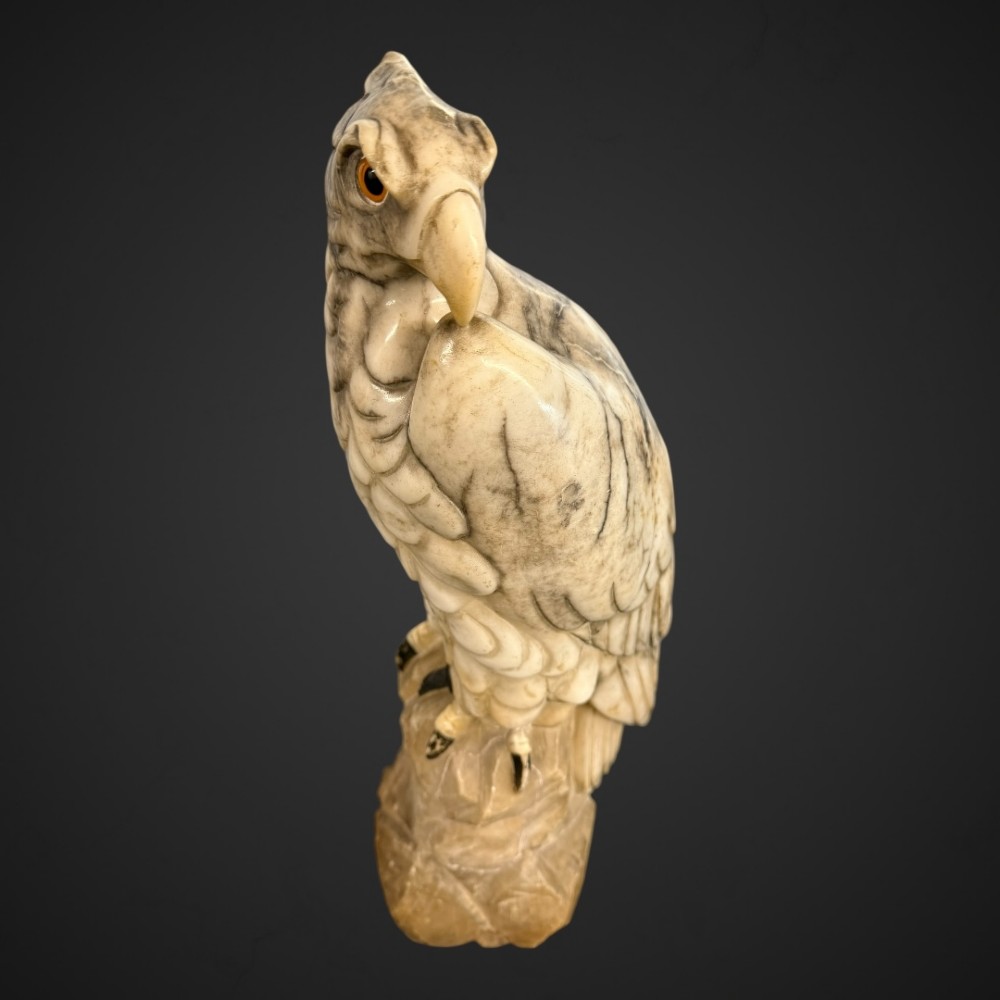 A 19th-century carved veined white marble eagle statue with amber glass eyes perched atop a rock formation. View V