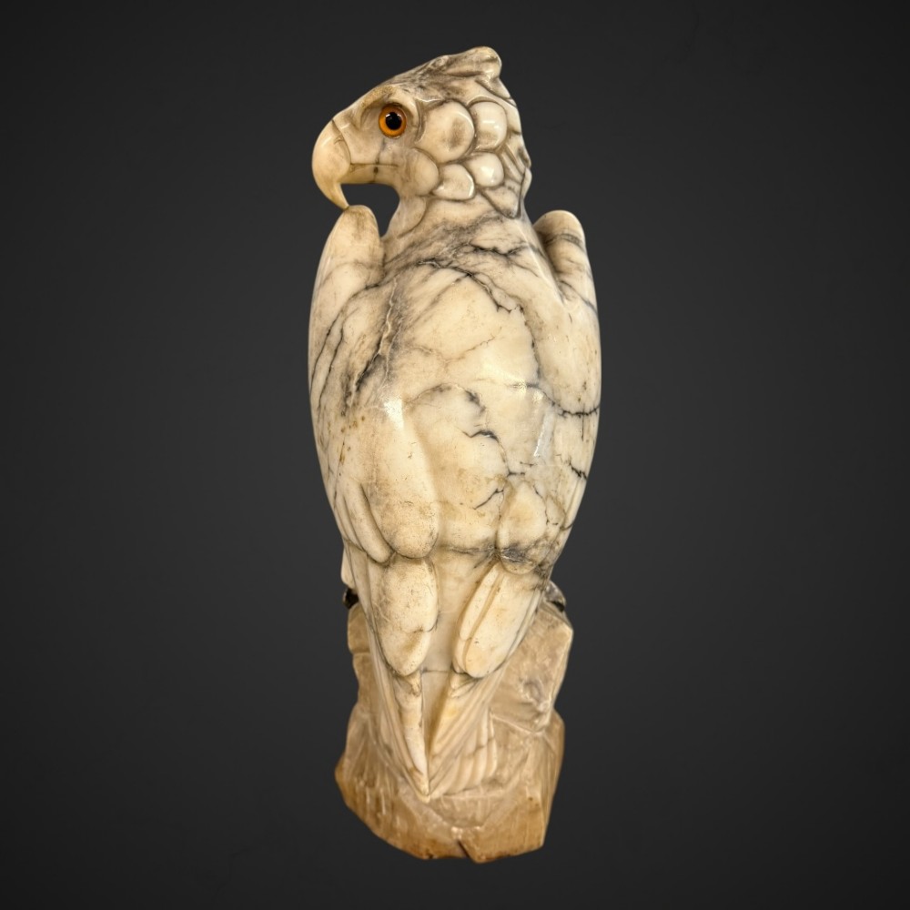 A 19th-century carved veined white marble eagle statue with amber glass eyes perched atop a rock formation. View VI