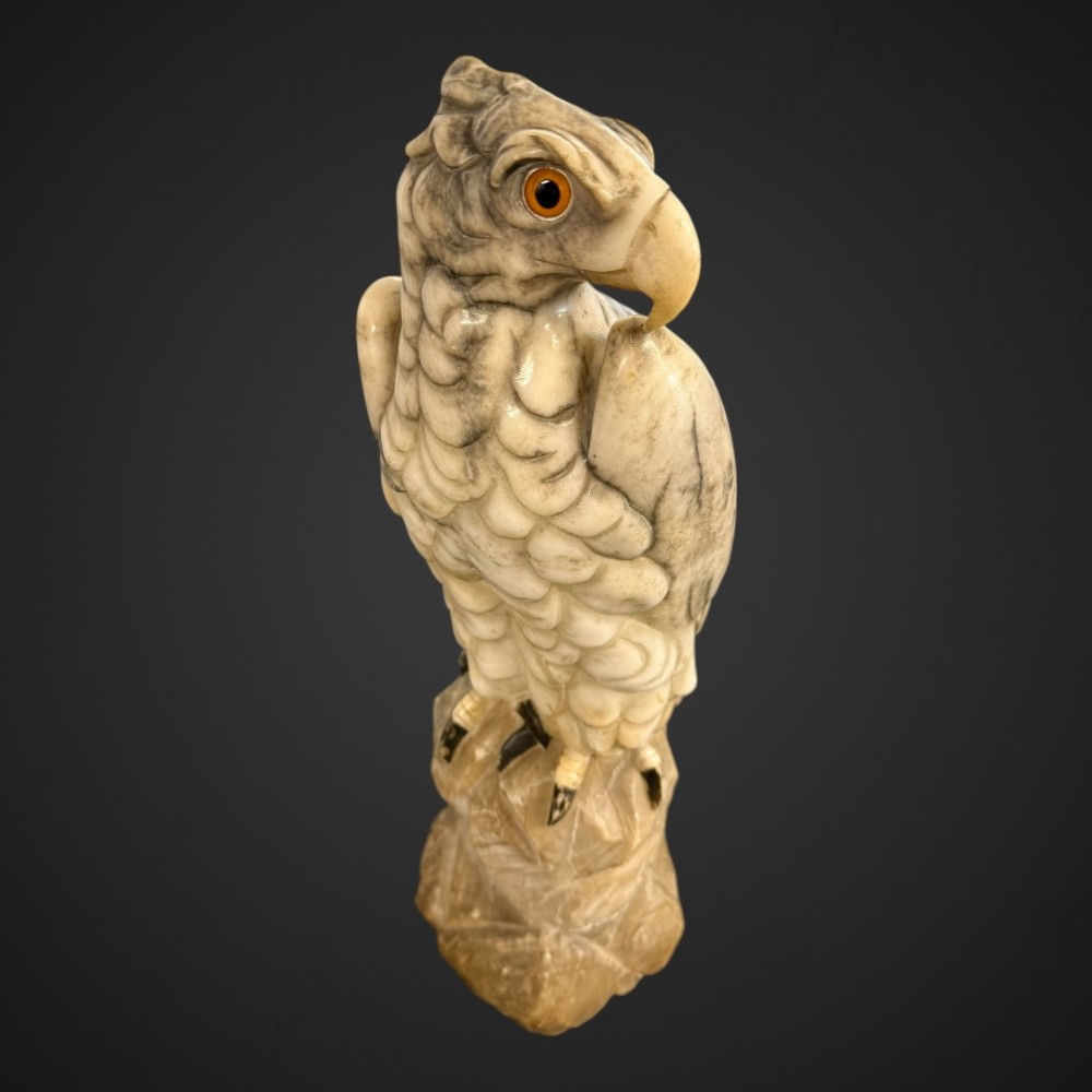 A 19th-century carved veined white marble eagle statue with amber glass eyes perched atop a rock formation. View VIII