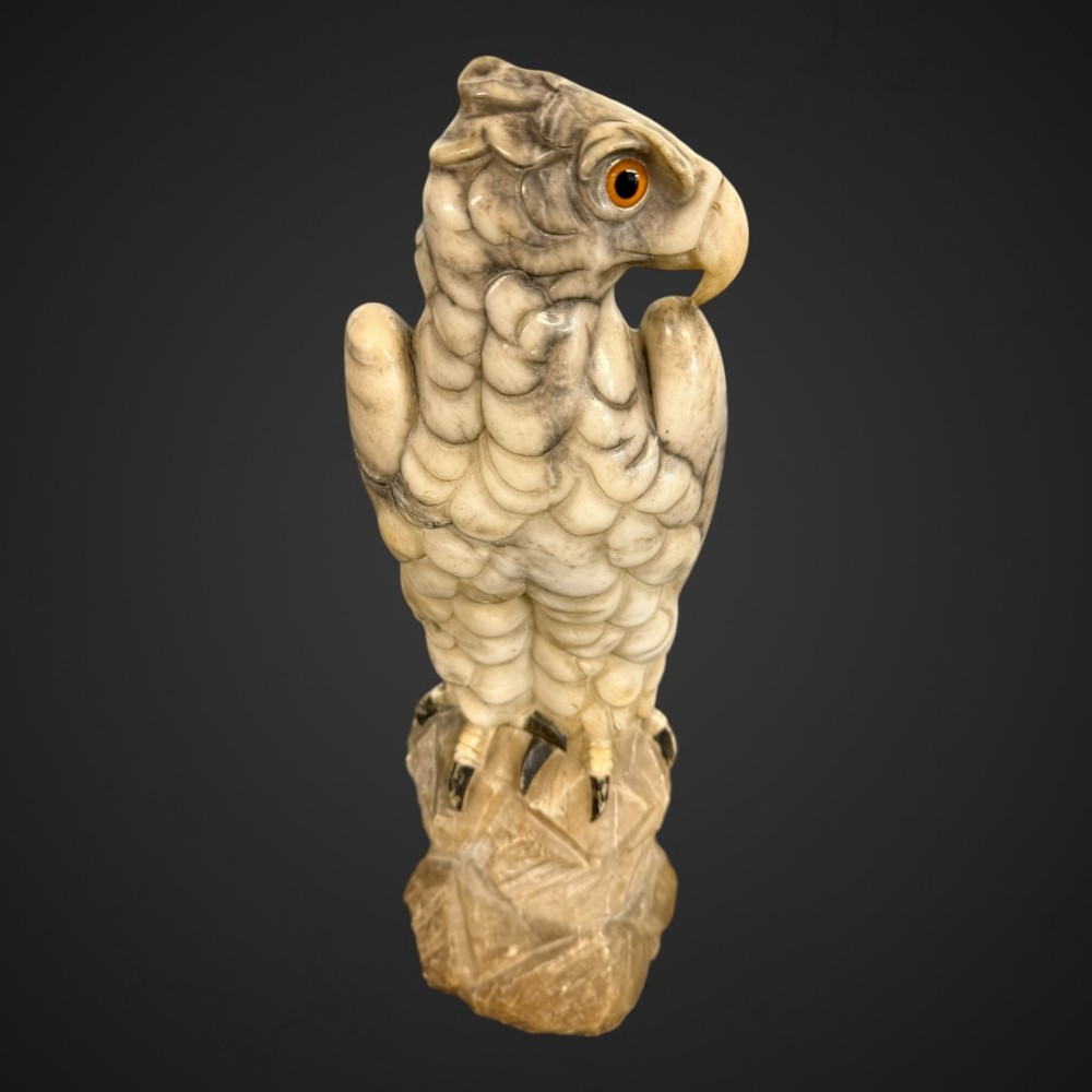 A 19th-century carved veined white marble eagle statue with amber glass eyes perched atop a rock formation. View IX