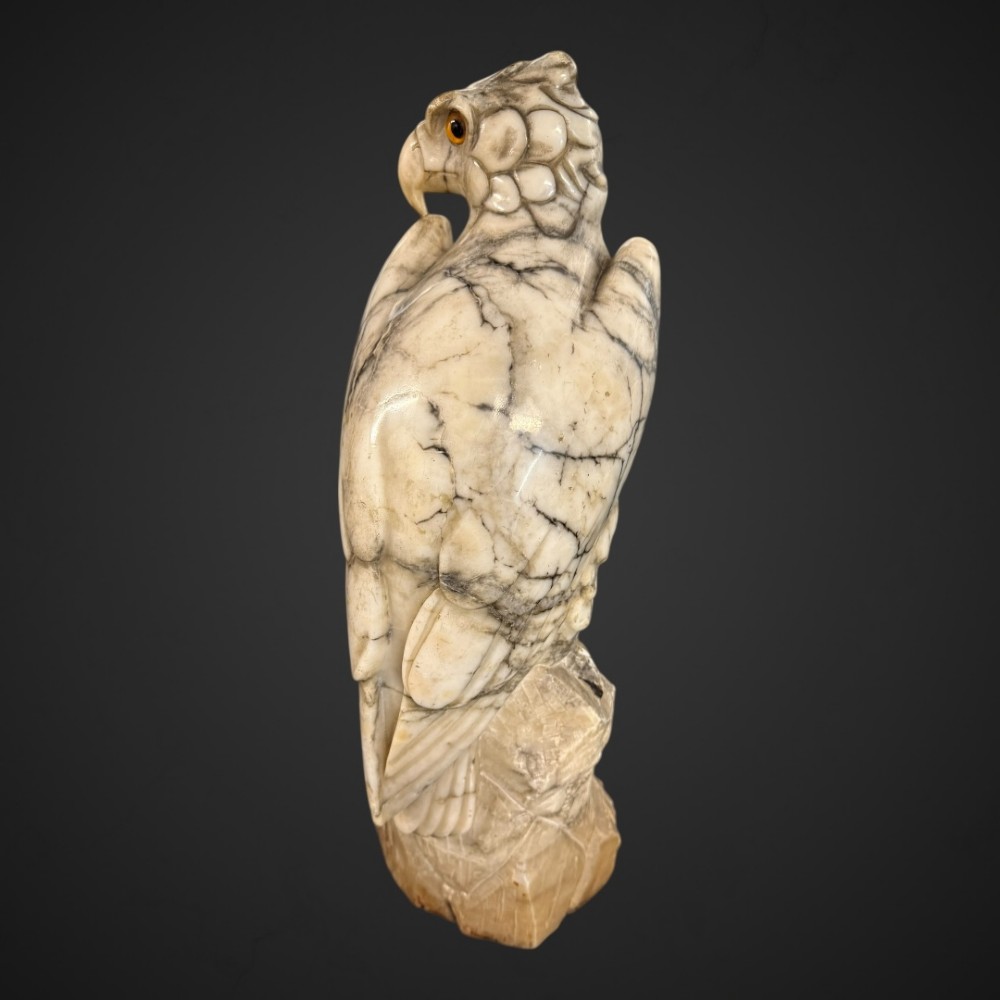 A 19th-century carved veined white marble eagle statue with amber glass eyes perched atop a rock formation. View X