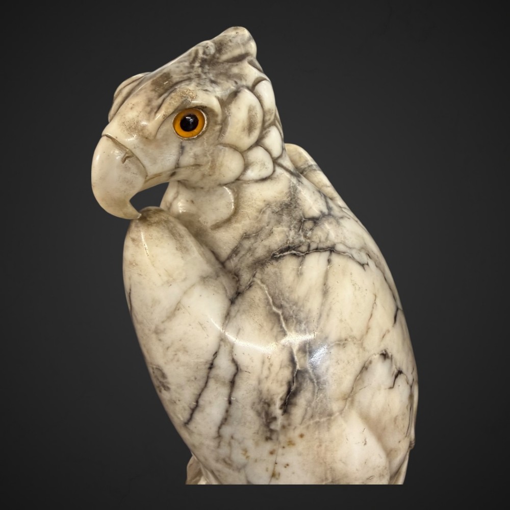 A 19th-century carved veined white marble eagle statue with amber glass eyes perched atop a rock formation. View XI
