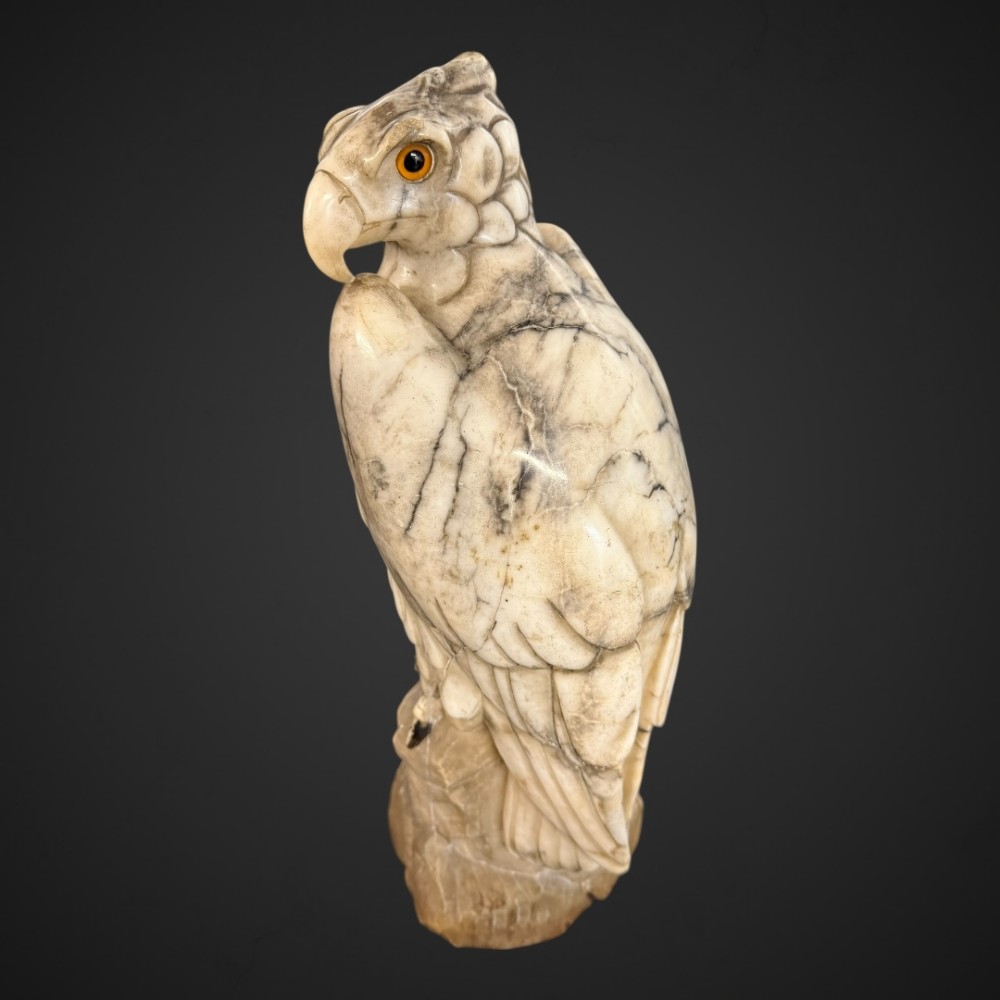 A 19th-century carved veined white marble eagle statue with amber glass eyes perched atop a rock formation. View XII