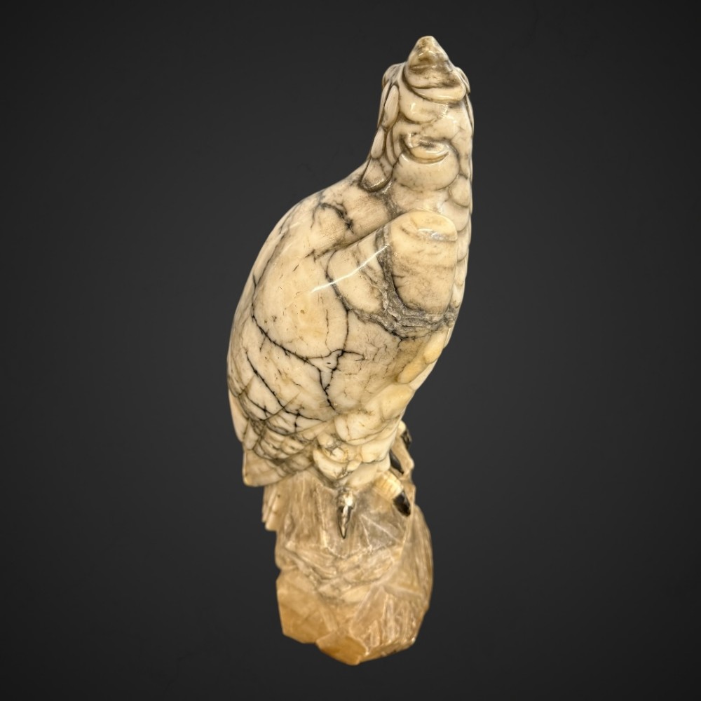 A 19th-century carved veined white marble eagle statue with amber glass eyes perched atop a rock formation. View XIV