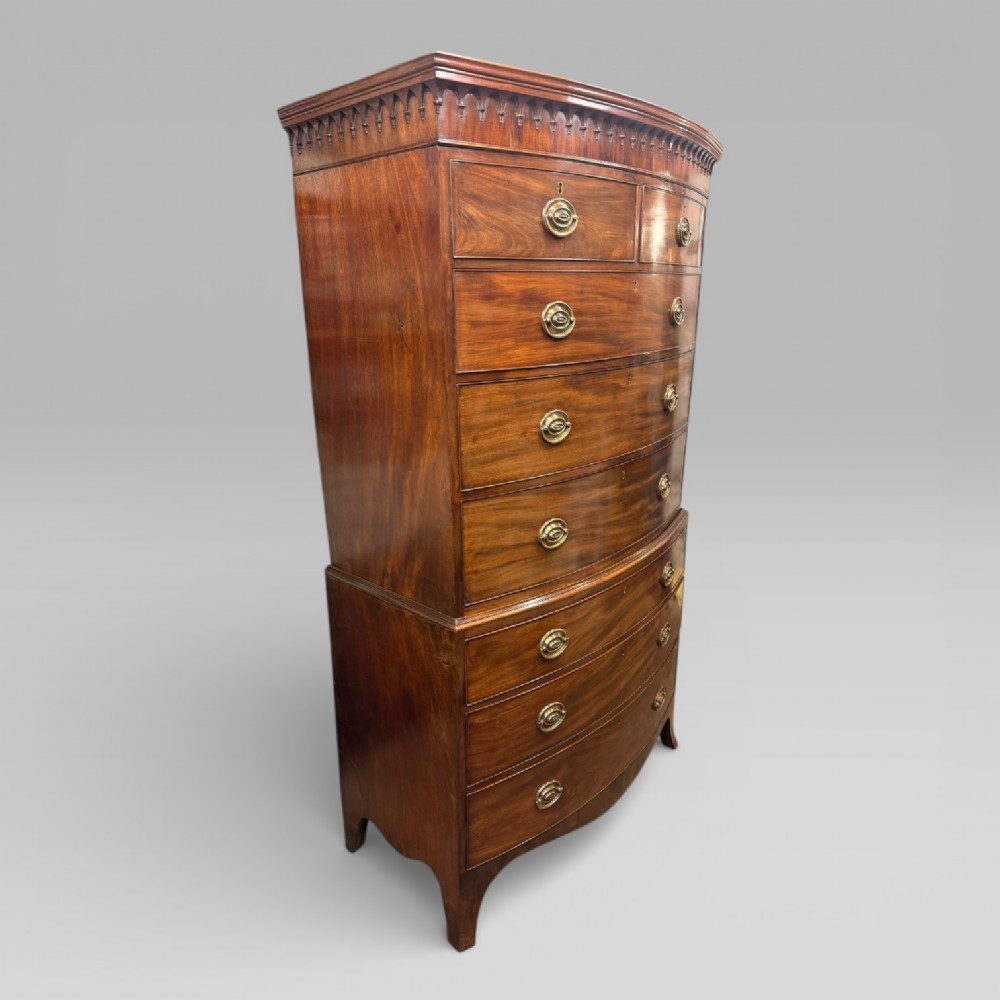 An antique Georgian mahogany bow-front chest on chest featuring two short over five long drawers with brass drop handles and an ornamental carved cornice. View III