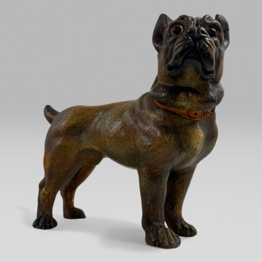 A dark brown painted terracotta dog sculpture standing upright with glass eyes and a moulded collar. View II