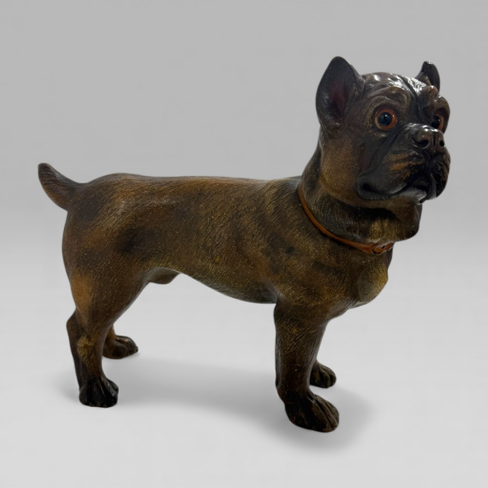 A dark brown painted terracotta dog sculpture standing upright with glass eyes and a moulded collar. View III