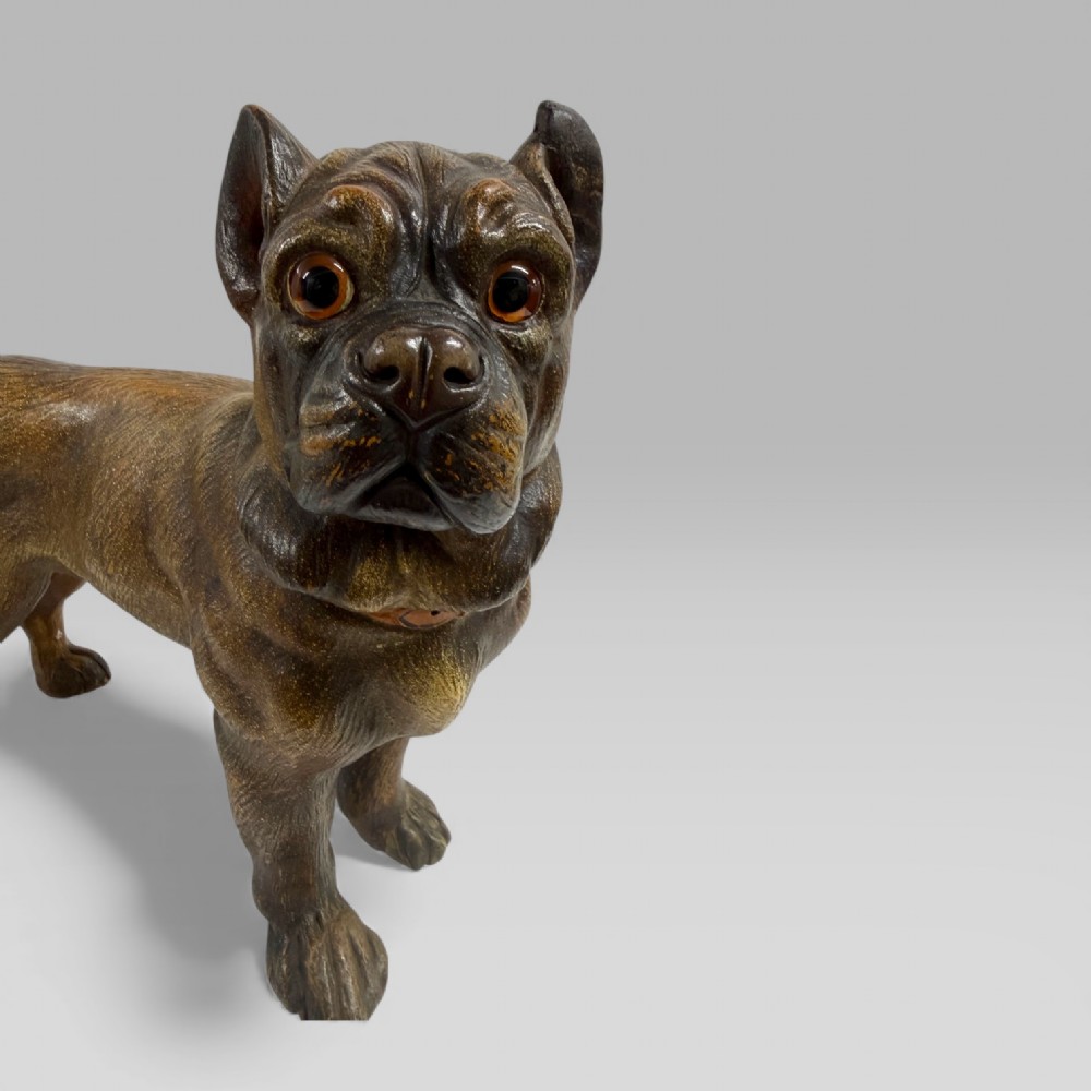 A dark brown painted terracotta dog sculpture standing upright with glass eyes and a moulded collar. View VI