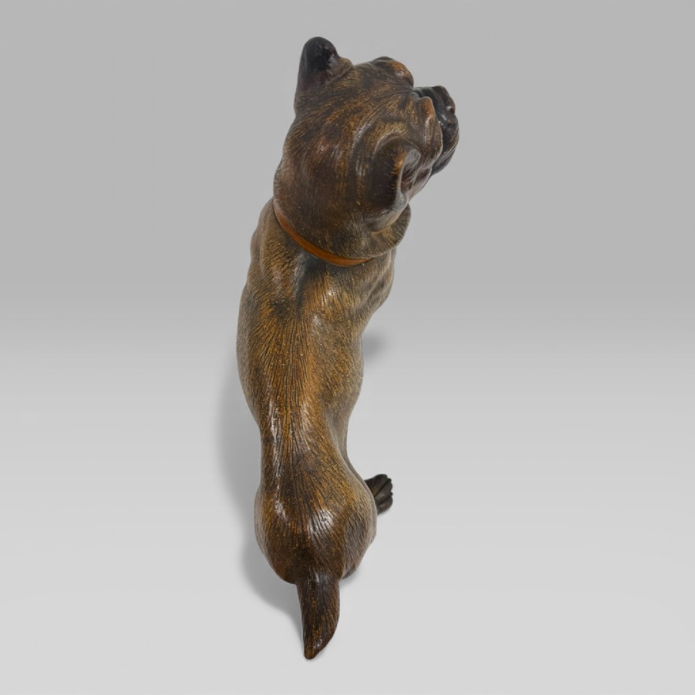 A dark brown painted terracotta dog sculpture standing upright with glass eyes and a moulded collar. View VIII