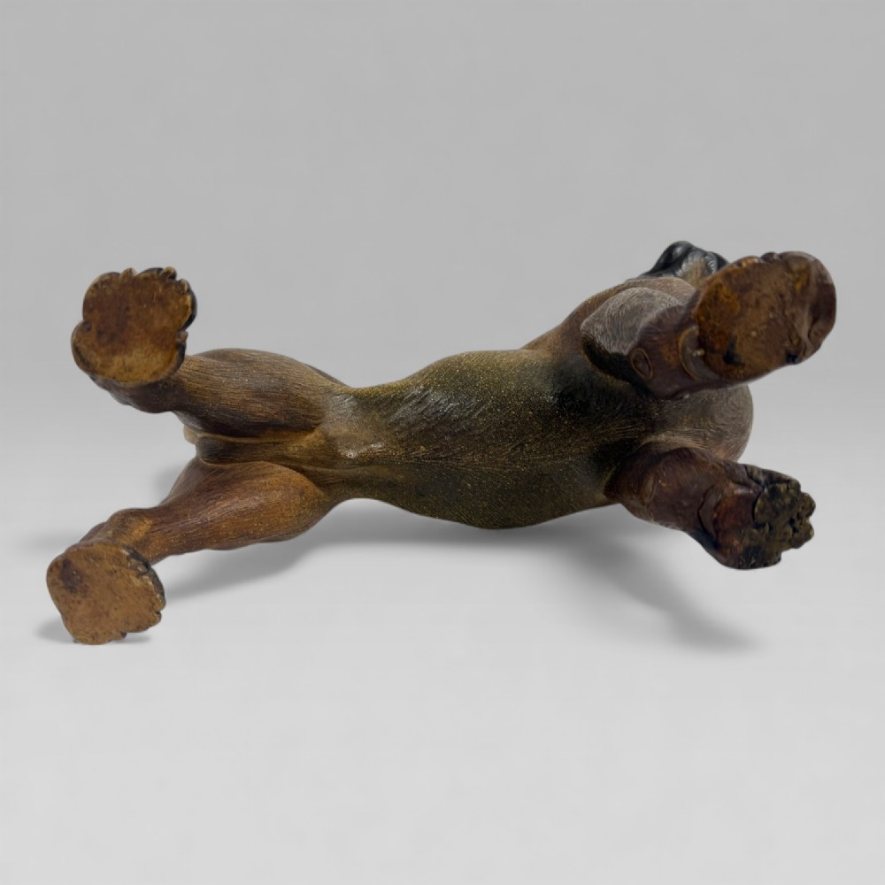A dark brown painted terracotta dog sculpture standing upright with glass eyes and a moulded collar. View X
