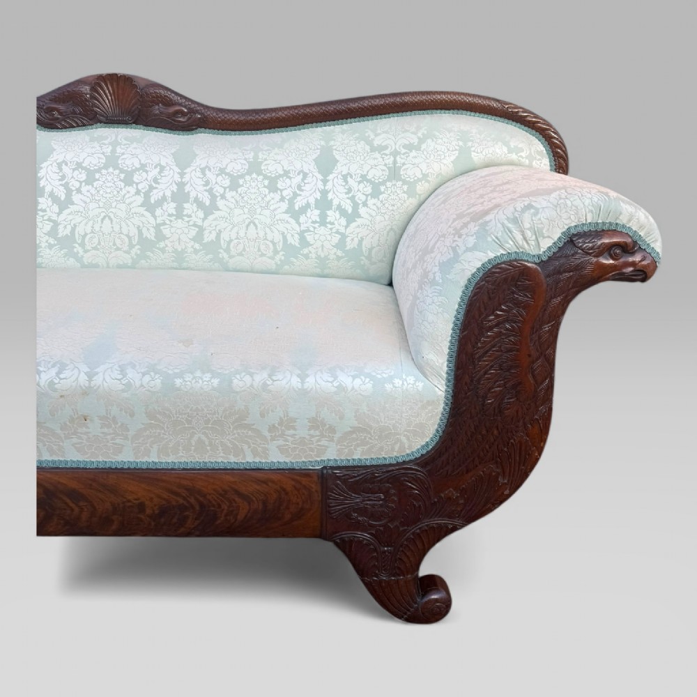 A nineteenth-century French Empire flame mahogany sofa featuring carved scroll arms, a serpentine crest, and light blue damask fabric upholstery. View IV